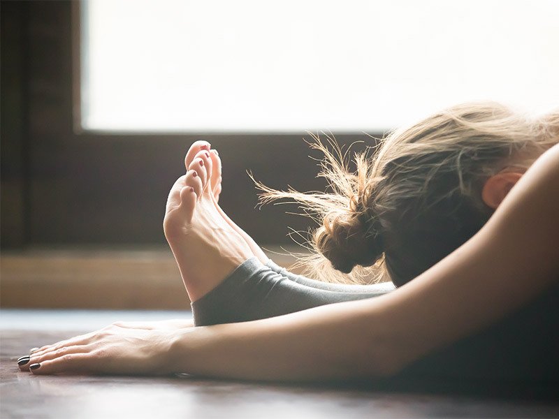 Life Extrension, woman stretching with her head on the legs and hands on the floor next  to her feet
